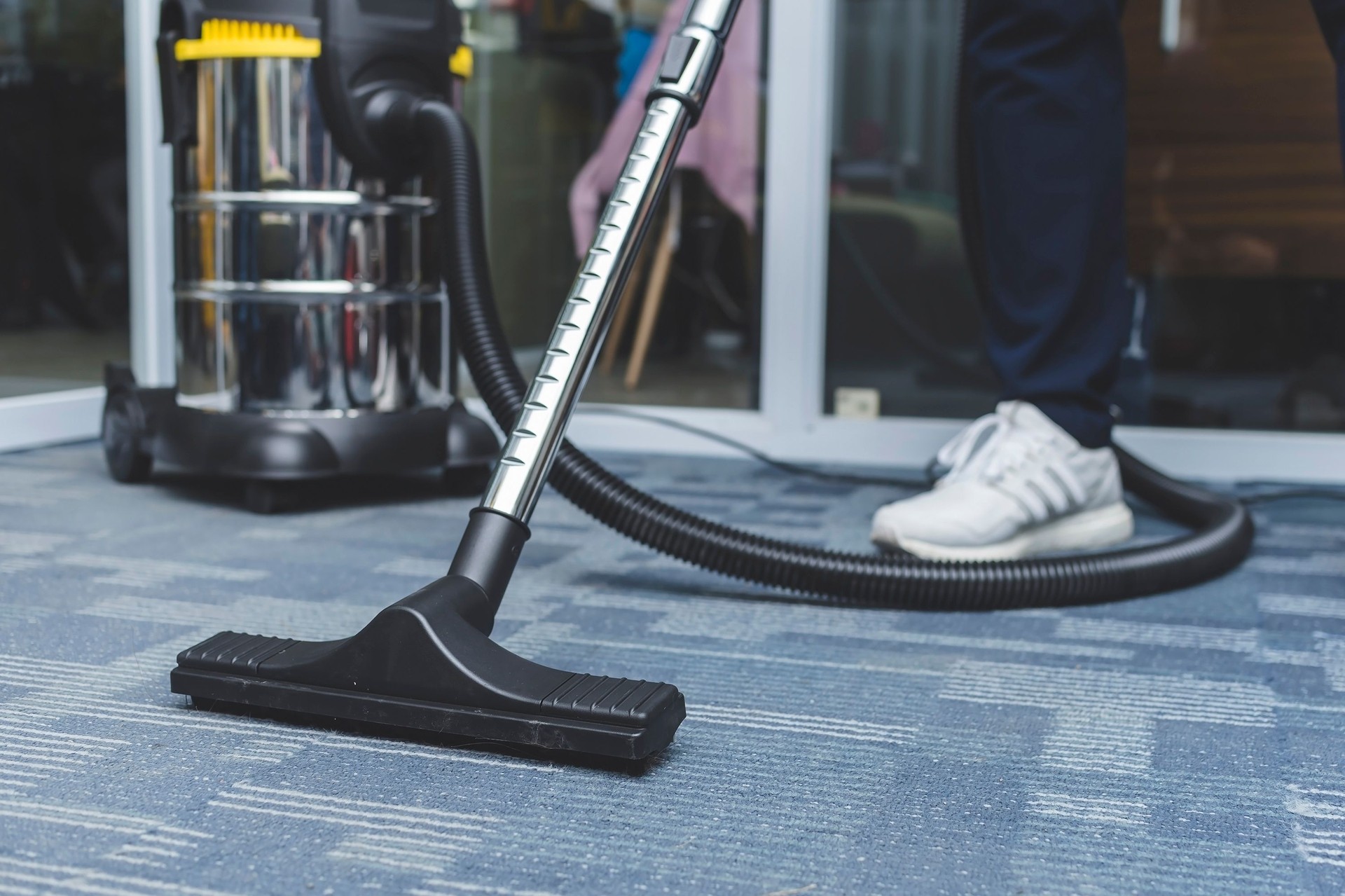 Janitor vacuum cleaning the corridor of an office building